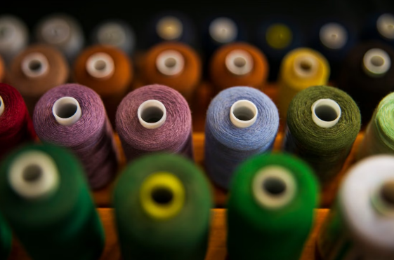 An assortment of colorful thread spools sits close together, showing the range a shop keeps in open stock.